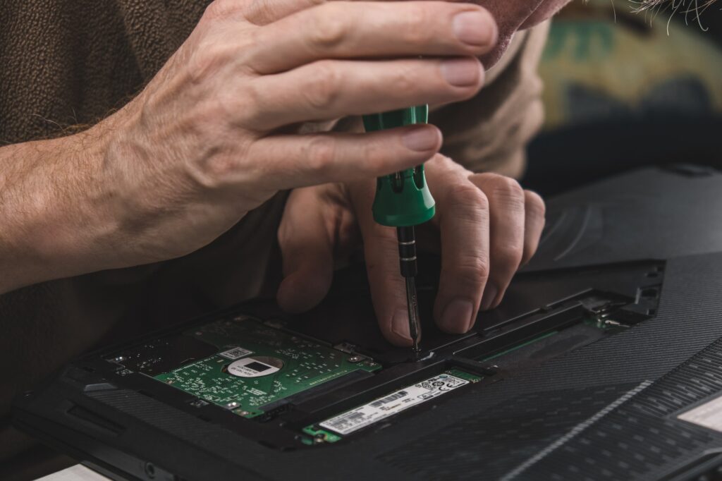 Installing and securing the hard drive into the laptop case after repair and maintenance. Close-up.